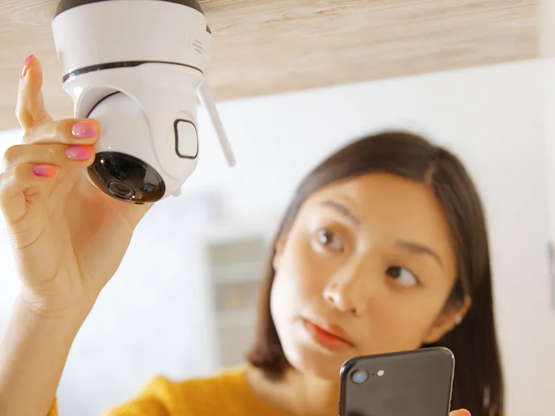 スマホ映像を見ながらカメラの取り付け位置を調整する女性